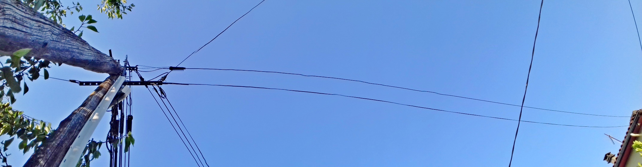 Raccordement aux deux réseaux d'une maison individuelle. Traverse et câble fibre optique au sommet du poteau